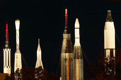 Historic rockets at the Space Center, lit up at night.