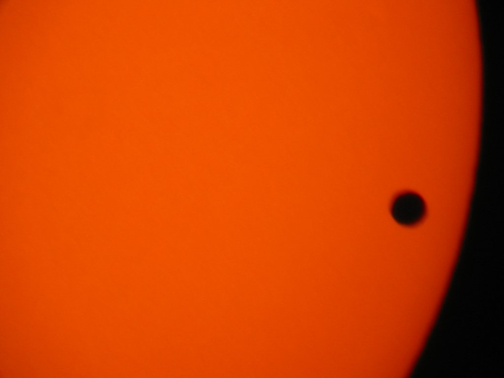 At this magnification the rotation of the earth quickly carried the planet and sun out of the telescopes's field of view. That's why the image is slightly motion-blurred. Only three large bodies come between the Sun and the Earth: Venus, the Moon (as seen from Iceland last year) and Mercury. The next Mercury transit is in 2006. It will be a much smaller dot than either Venus or (certainly) the Moon.  Digiscoped with Canon S330 camera and Meade ETX 125 telescope, June 2004.  Click for next photo.