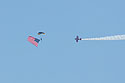 Skydiver brings in the flag, Sioux Falls Air Show.  Lucas Oil stunt plane escorts him down.
