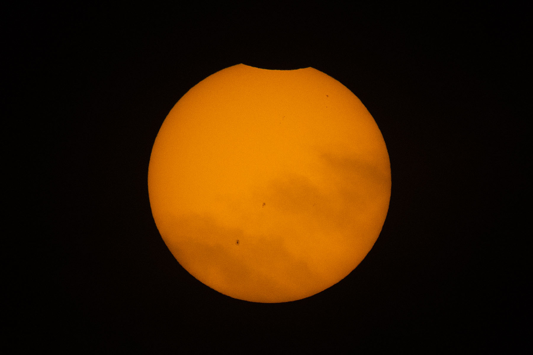 Annular solar eclipse, switching to a different camera, some clouds at the start of the partial phase, 80 minutes before peak.  Film solar filter on 100-400mm camera lens, 1.4x extender, Canon R10 camera.  Click for next photo.