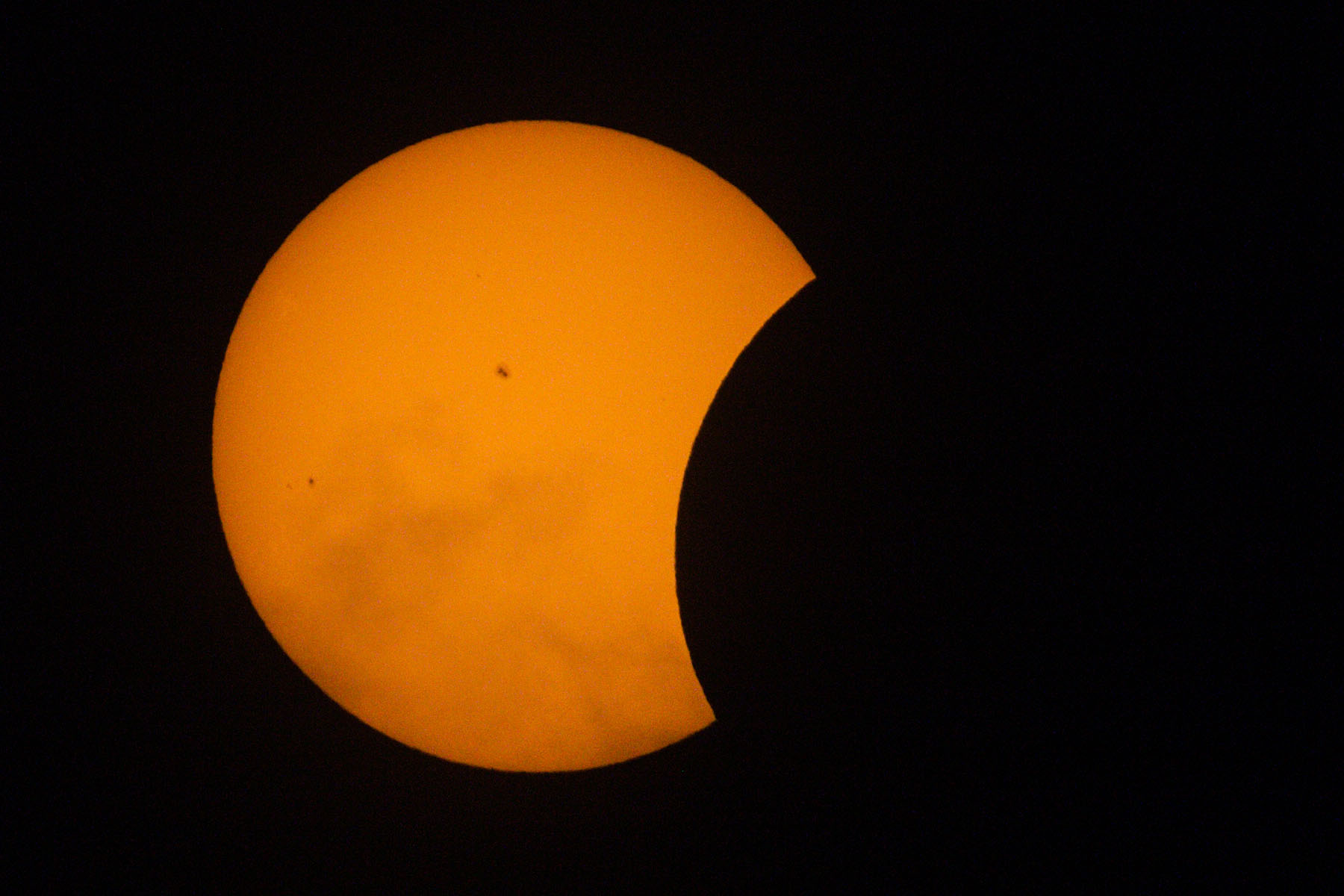 Start of the partial phase of the eclipse, orange mylar filter.  Some thin clouds in the lower half.  Click for next photo.